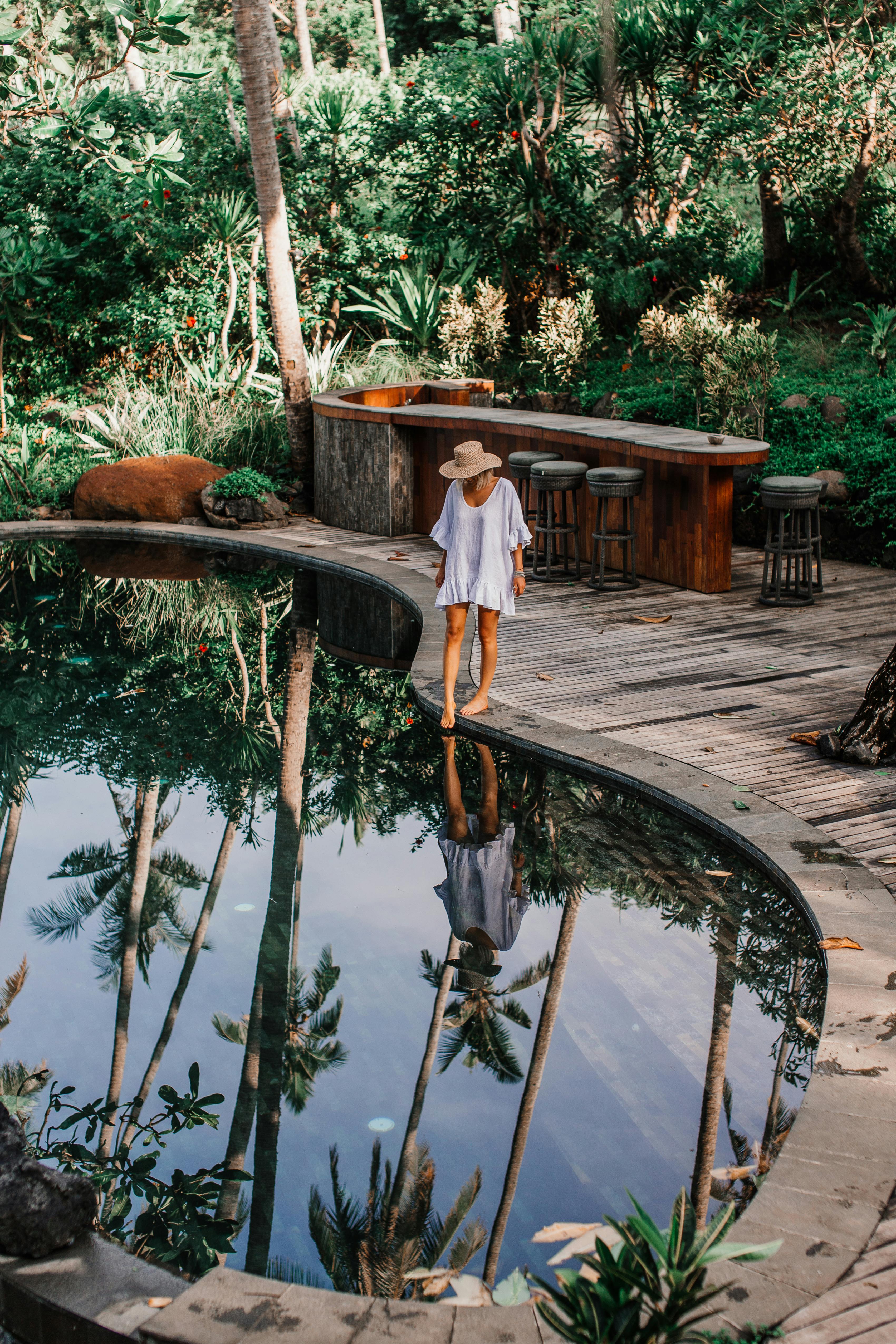 woman wearing a hat standing beside a pool