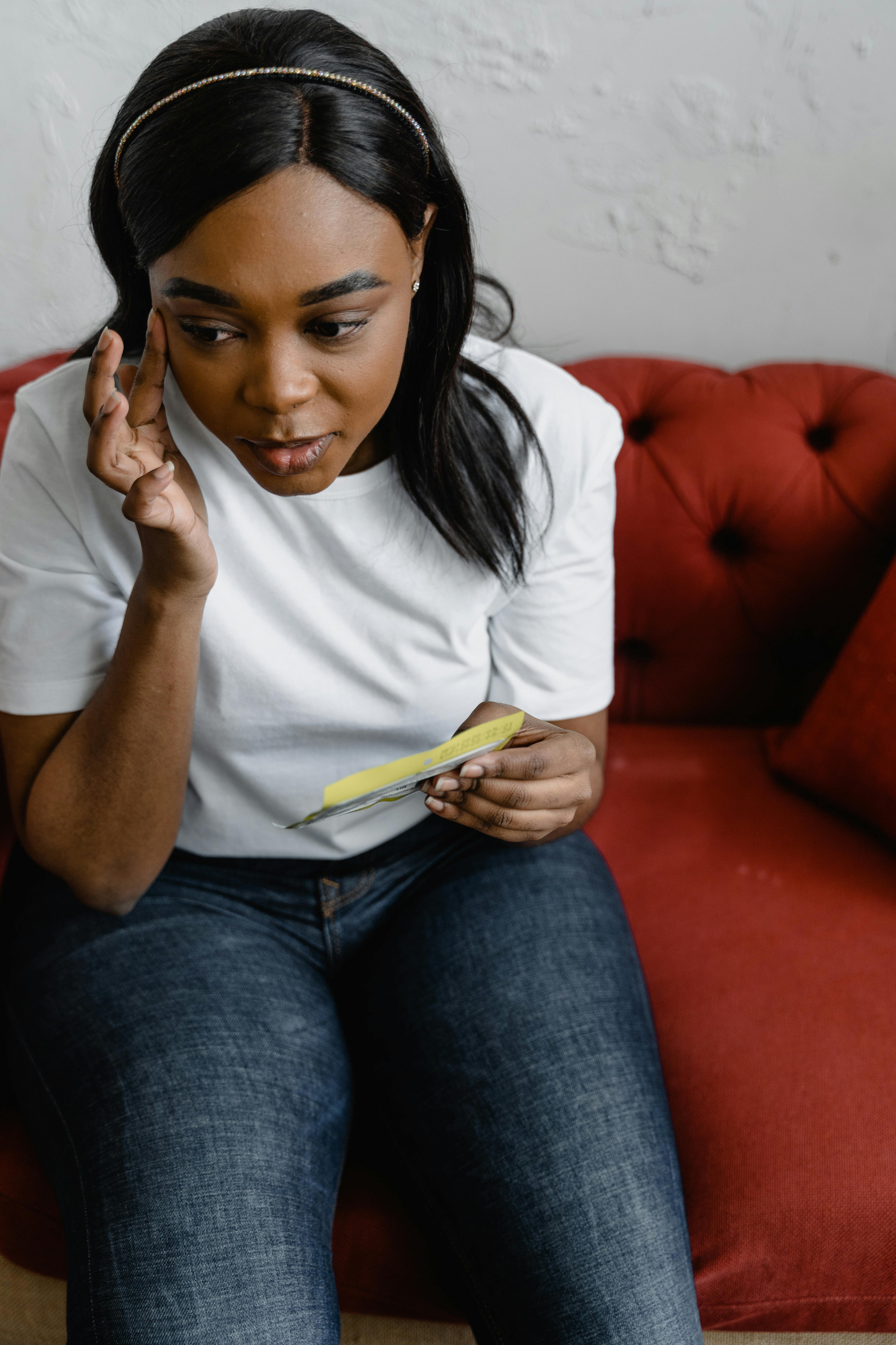 woman in white crew neck t shirt and blue denim jeans sitting on red couch