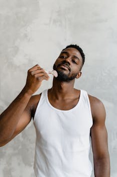 Portrait of a young man using a jade roller for facial massage in a studio setting.