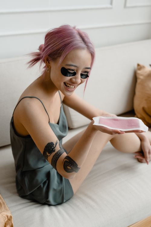 Free Smiling woman with pink hair using skincare products indoors. Stock Photo