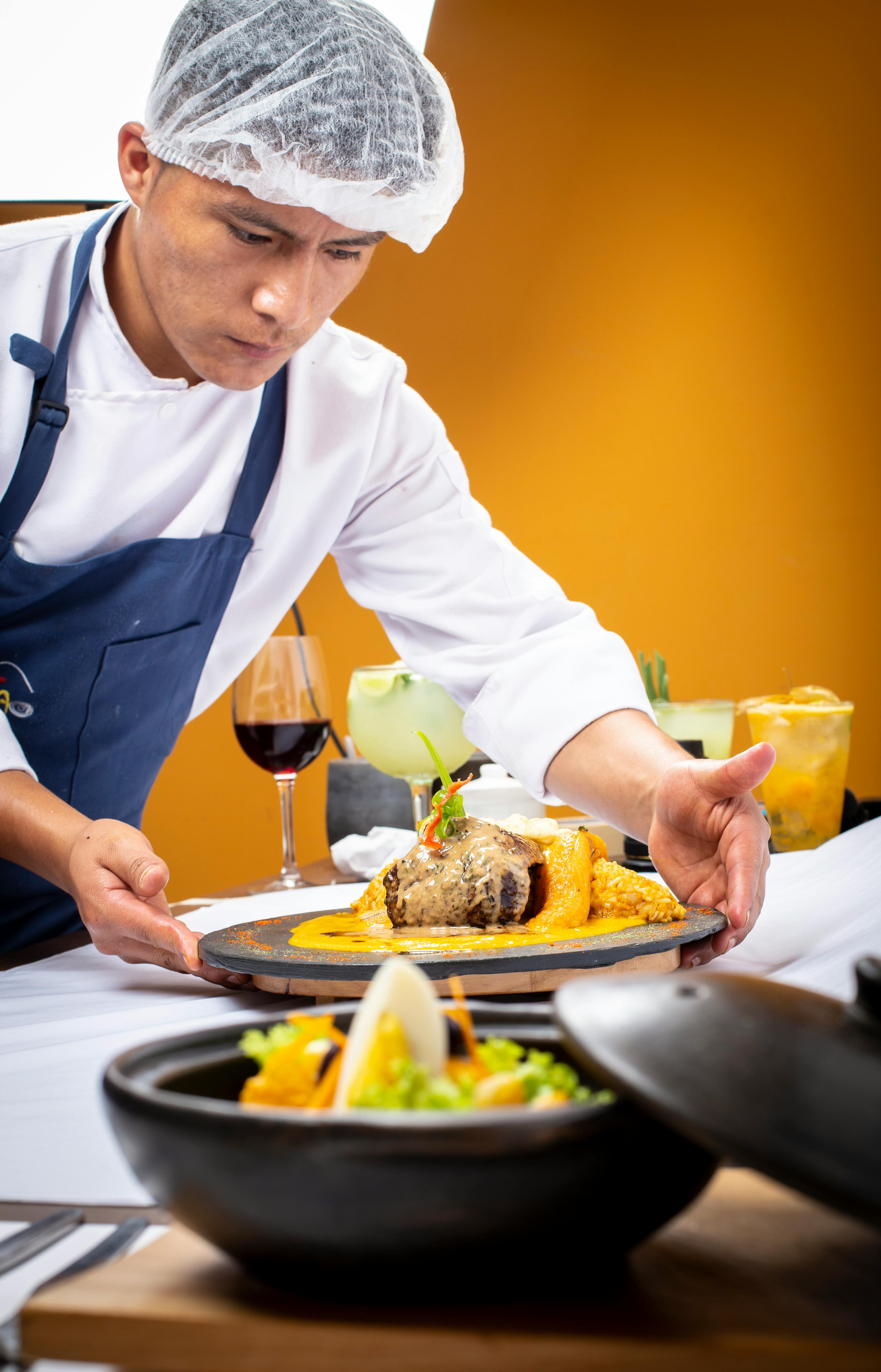 A chef looking amused while holding a plate of food that looks intentionally bizarre.