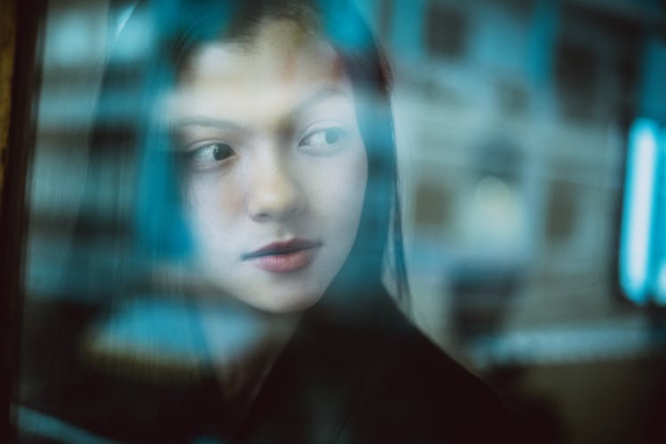 Crop Charming Asian Woman With Dreamy Gaze Behind Glass Wall