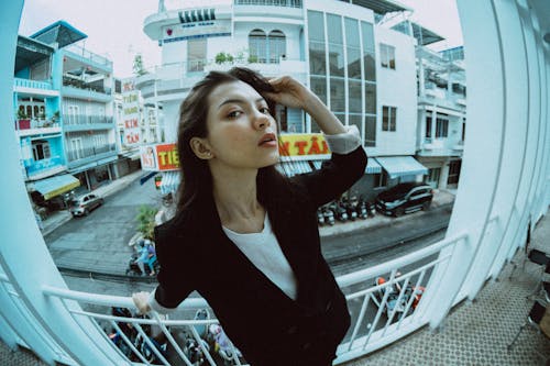 Stylish Asian woman on balcony against urban houses