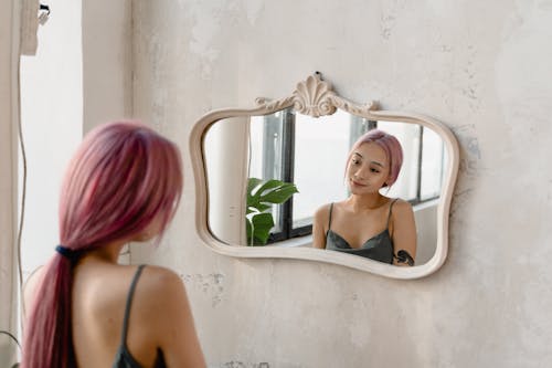 Free A Woman with Pink Hair Looking at Her Reflection on the Mirror Stock Photo