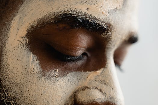 Close-up of a person applying facial clay mask for skincare routine.