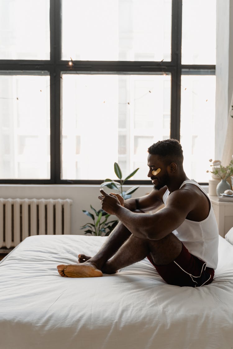 Man In White Tank Top Sitting On Bed