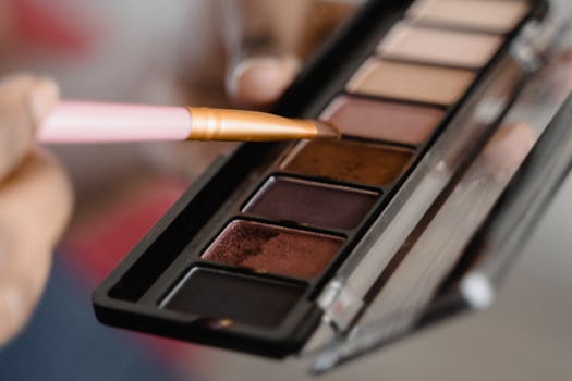 A detailed close-up of an eyeshadow palette with a makeup brush in use.