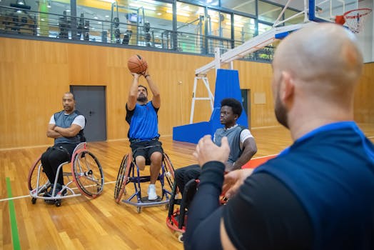 Athletes in wheelchairs playing basketball indoors, focused on teamwork and determination.