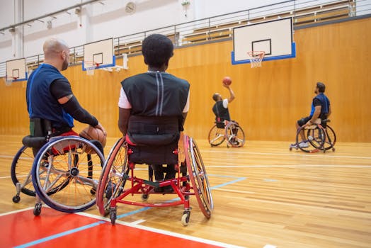 Athletes playing wheelchair basketball during a training session in an indoor sports hall.