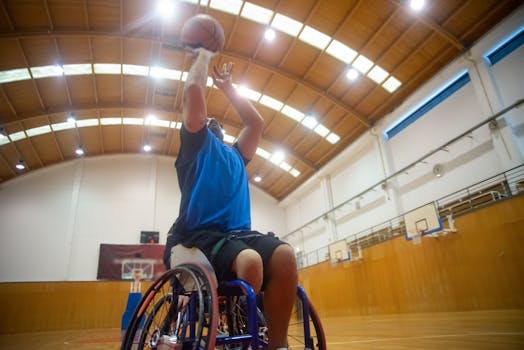 Athlete in a wheelchair shooting a basketball in a well-lit indoor court.