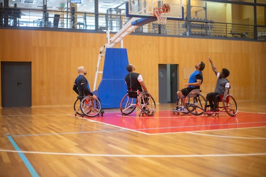 Athletes playing wheelchair basketball in a sports hall, showcasing teamwork and skill.