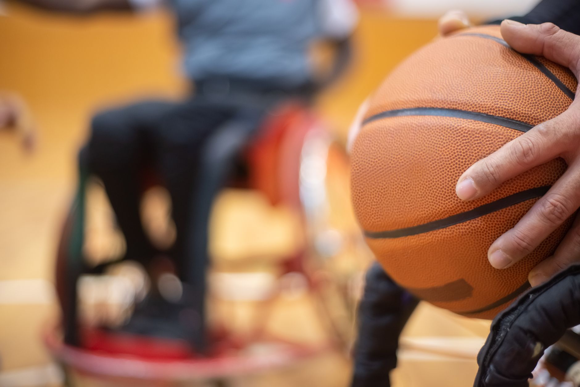 close-up of a basketball player’s hands controlling a ball during low fingertip dribbles inside a gym