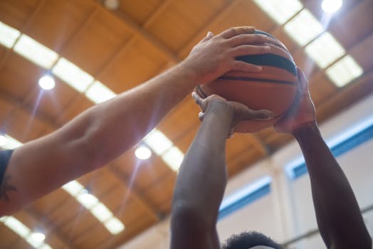 Close-up shot of players competing for the basketball in an indoor court.