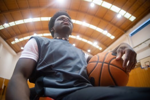 Low-angle shot of a basketball player holding a ball in an indoor court.