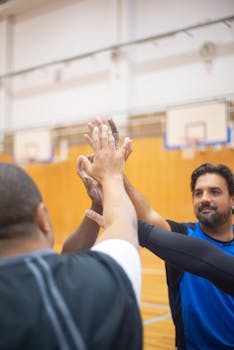 Group of athletes sharing a motivational high-five during an indoor basketball session.