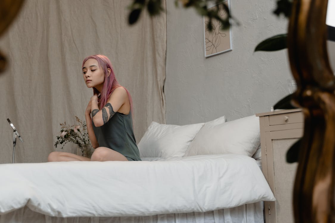 Free Woman Doing Skin Care Routine while Sitting on Bed Stock Photo