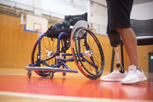Free Close-up of a wheelchair and prosthetic leg on a basketball court emphasizing adaptive sports. Stock Photo