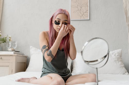 Free Woman with Pink Hair Applying Eye Patches Stock Photo