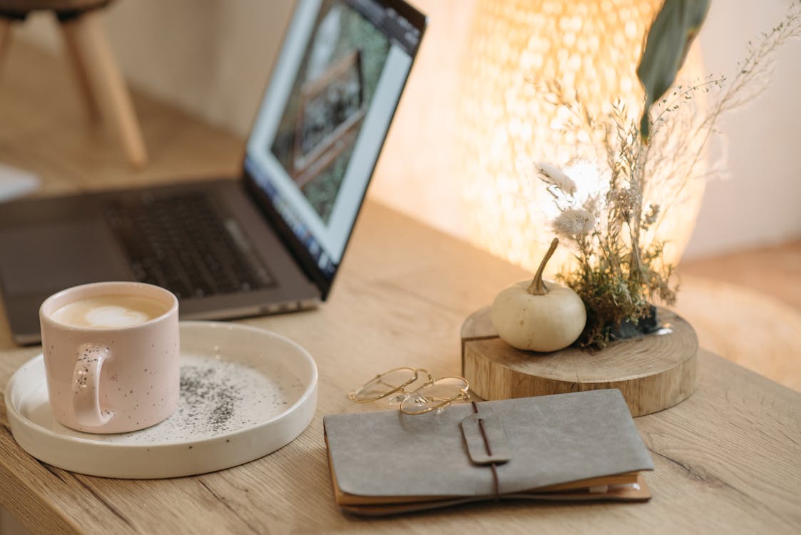 Free Macbook Pro Beside White Ceramic Mug on Brown Wooden Table Stock Photo