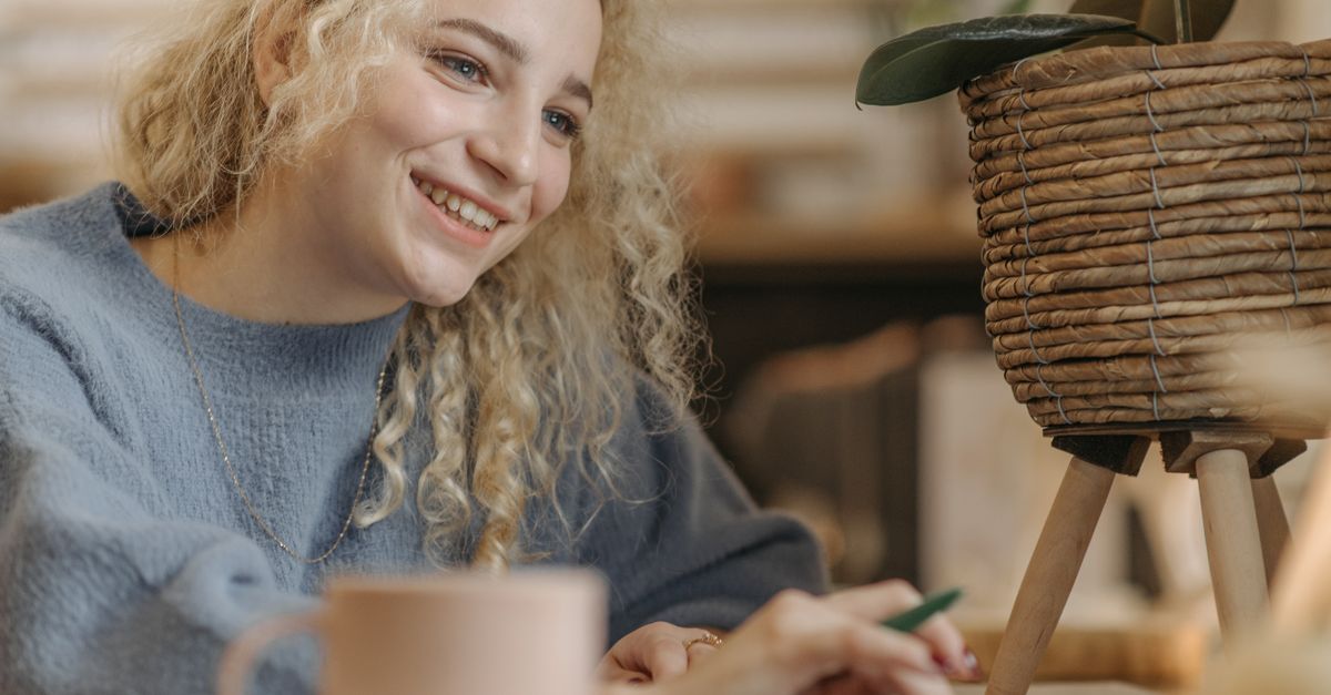 A person smiling while working from a hammock or a cozy coffee shop — showing that work can be enjoyable