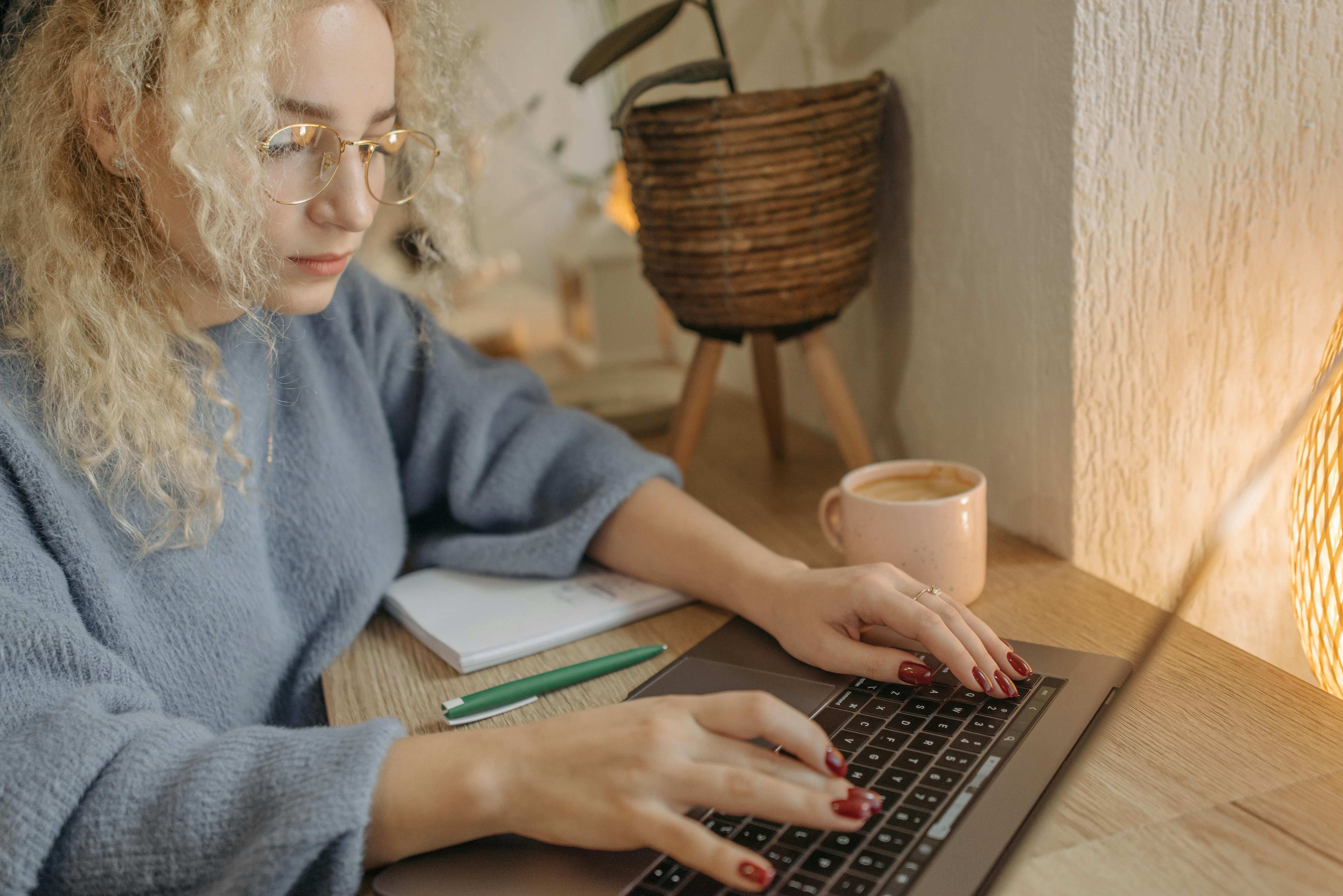 Focused woman with curly hair working on a laptop in a cozy indoor setting.