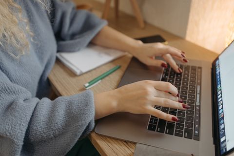 Hands typing an article on a laptop