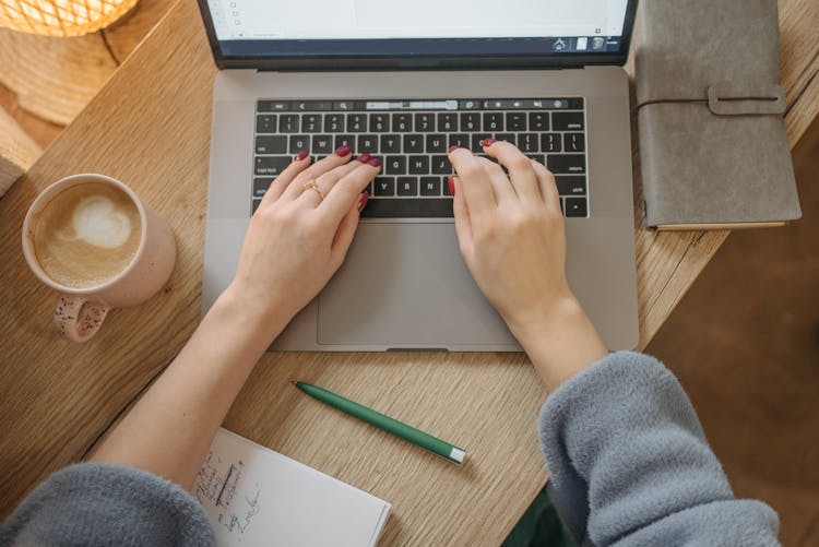 Person Using Macbook Pro On Brown Wooden Table