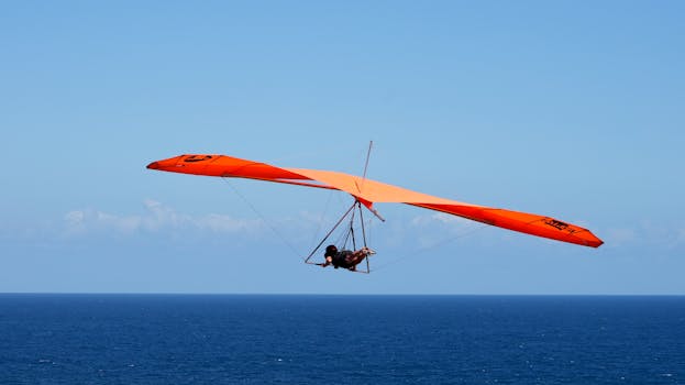 Hang glider soaring over the ocean on a clear, sunny day. Perfect for adventure enthusiasts.