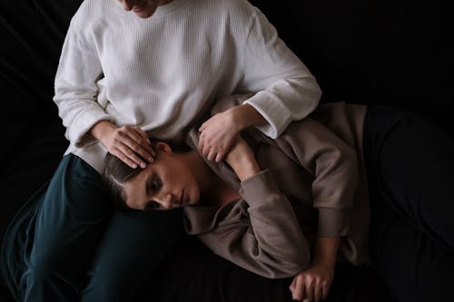 Woman in White Turtleneck Sweater Lying on Black Textile