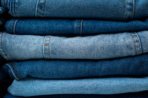 Free A close-up view of stacked blue denim jeans showcasing various shades of indigo fabric. Stock Photo