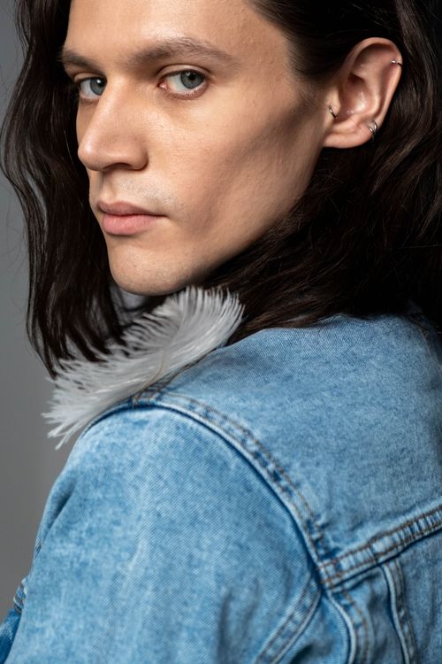 Free Close-up portrait of a young caucasian individual in a denim jacket. Studio lighting creates a dramatic effect. Stock Photo