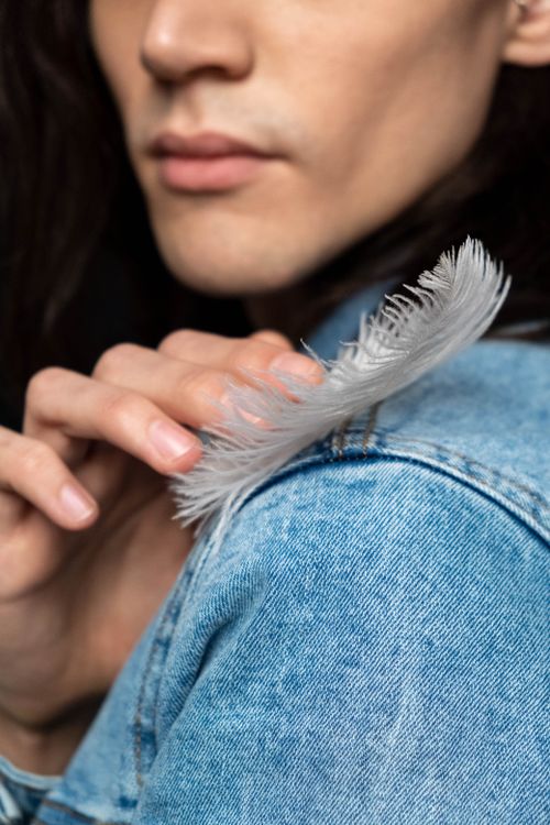 Free Artistic shot of a woman in denim with feather and delicate touch. Stock Photo