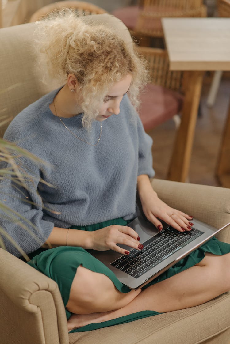 A Woman In Gray Sweater Typing On Laptop