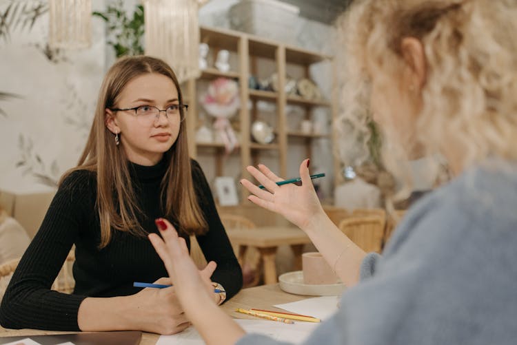 Woman In Black Shirt Listening To Her Colleague While In A Meeting