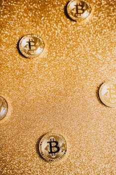 Golden Bitcoin coins scattered on a glittering gold surface, highlighting cryptocurrency.