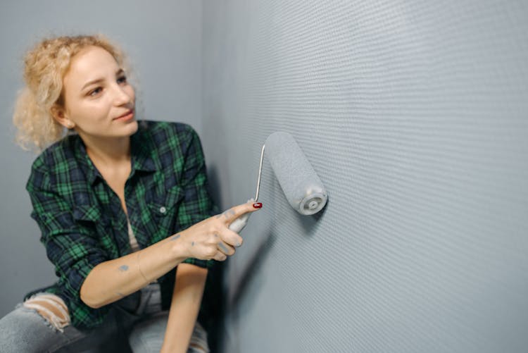 Woman Painting A Wall With A Roller Paint Brush 