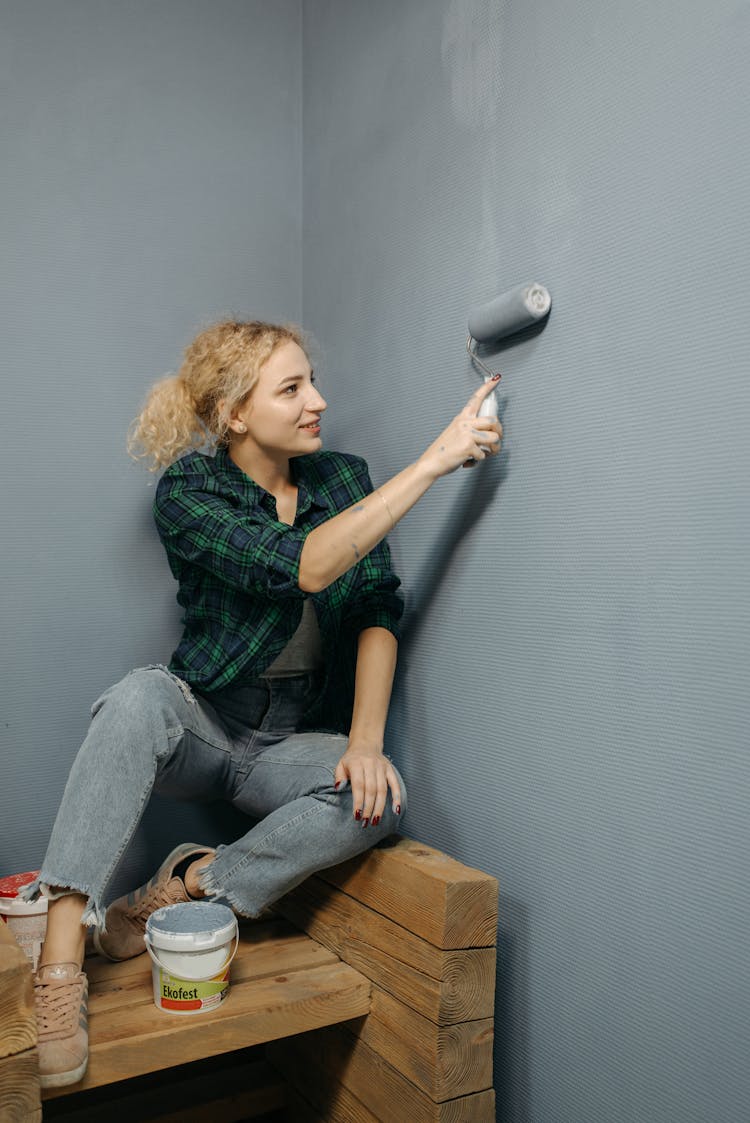 Woman Painting A Room With A Roller Paint Brush