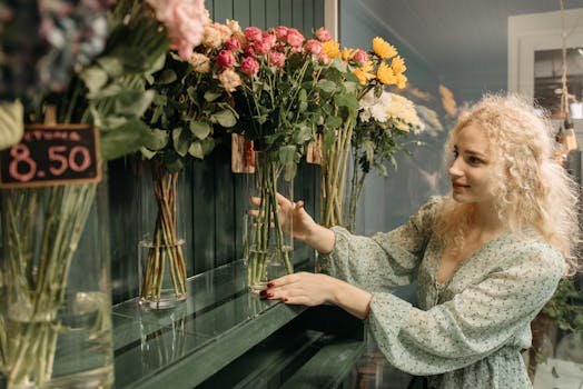 A cheerful woman arranging vibrant flowers in a cozy floral shop indoor setting.