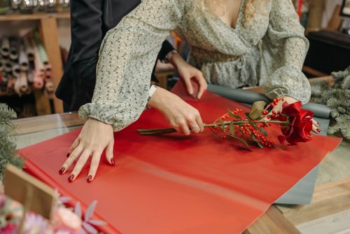 Free Florist arranging a flower bouquet with red blooms in a shop setting. Stock Photo