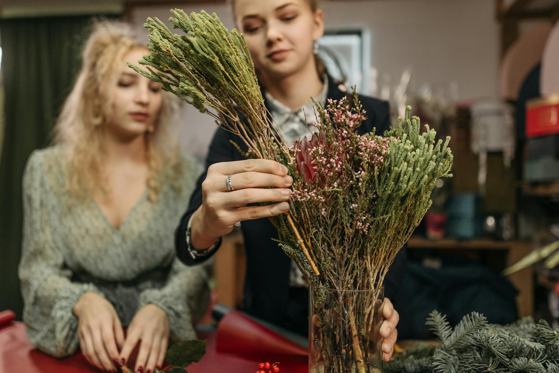 Two women working together on a floral arrangement in a cozy flower shop setting.