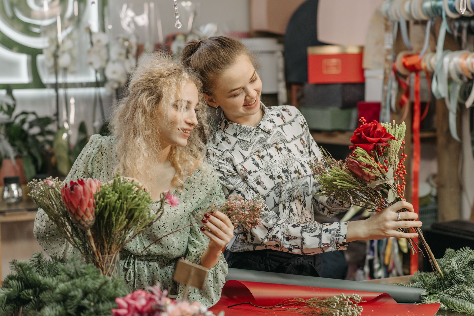 Two women florists happily arranging a flower bouquet in their charming shop.