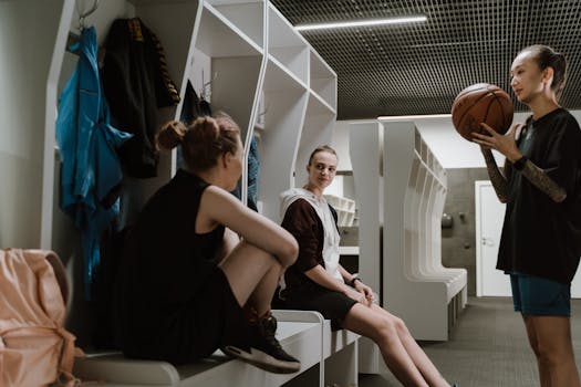 Three women basketball players chatting in a modern locker room setting.