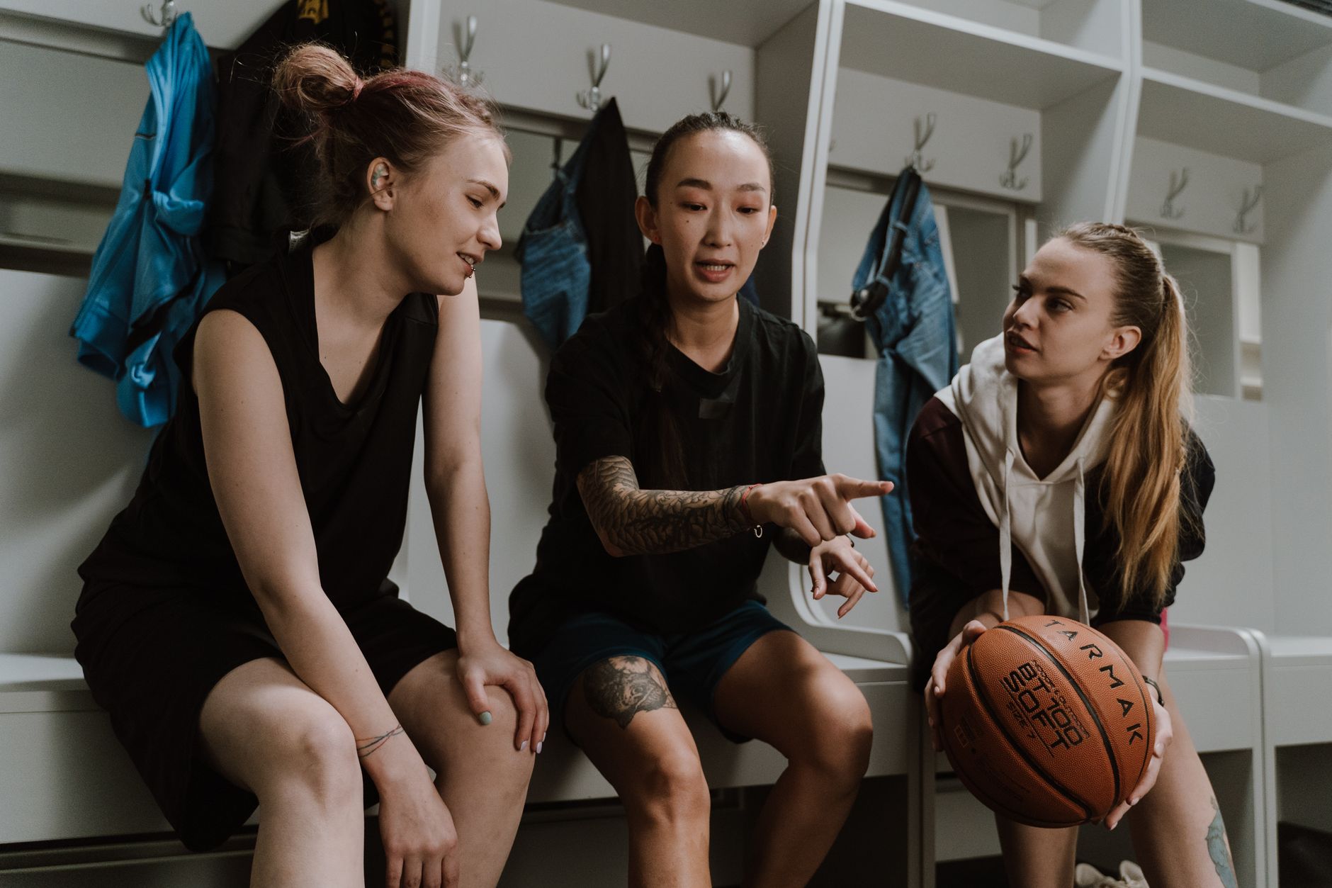 Three teenagers in a locker room strategizing before a basketball game.