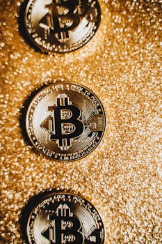 Three Bitcoin coins on a shimmering gold background, symbolizing digital wealth.