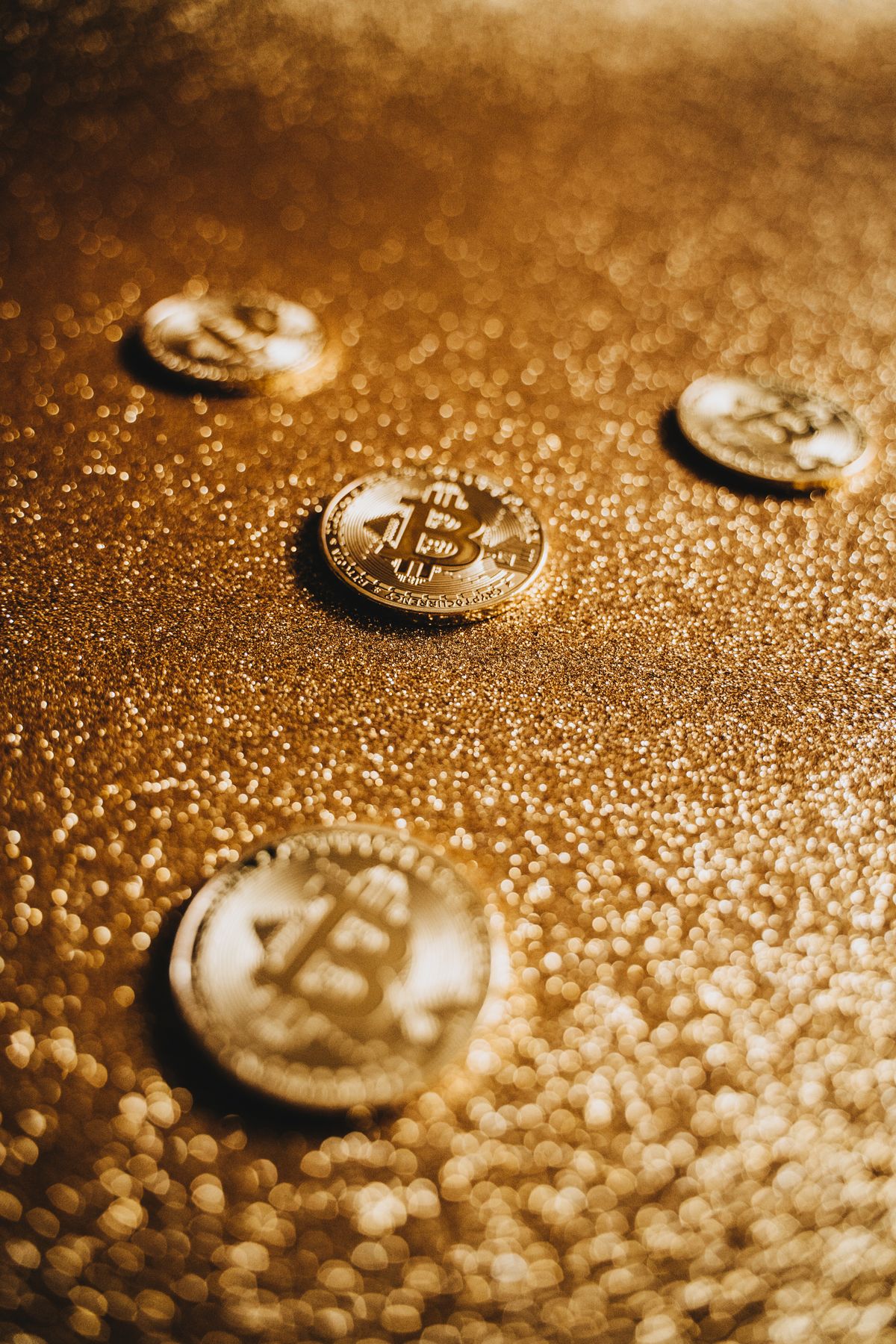 Golden bitcoin coins scattered on a glittering golden surface