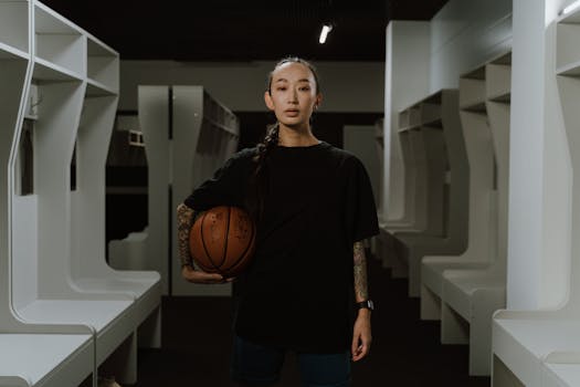 Portrait of a sportswoman standing confidently in a locker room holding a basketball.