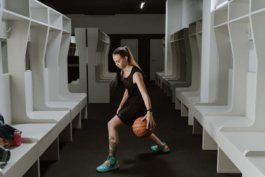 A female basketball player practicing dribbling in a modern indoor locker room.