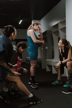 Empowered women's basketball team discussing strategy in the locker room for motivation and teamwork.
