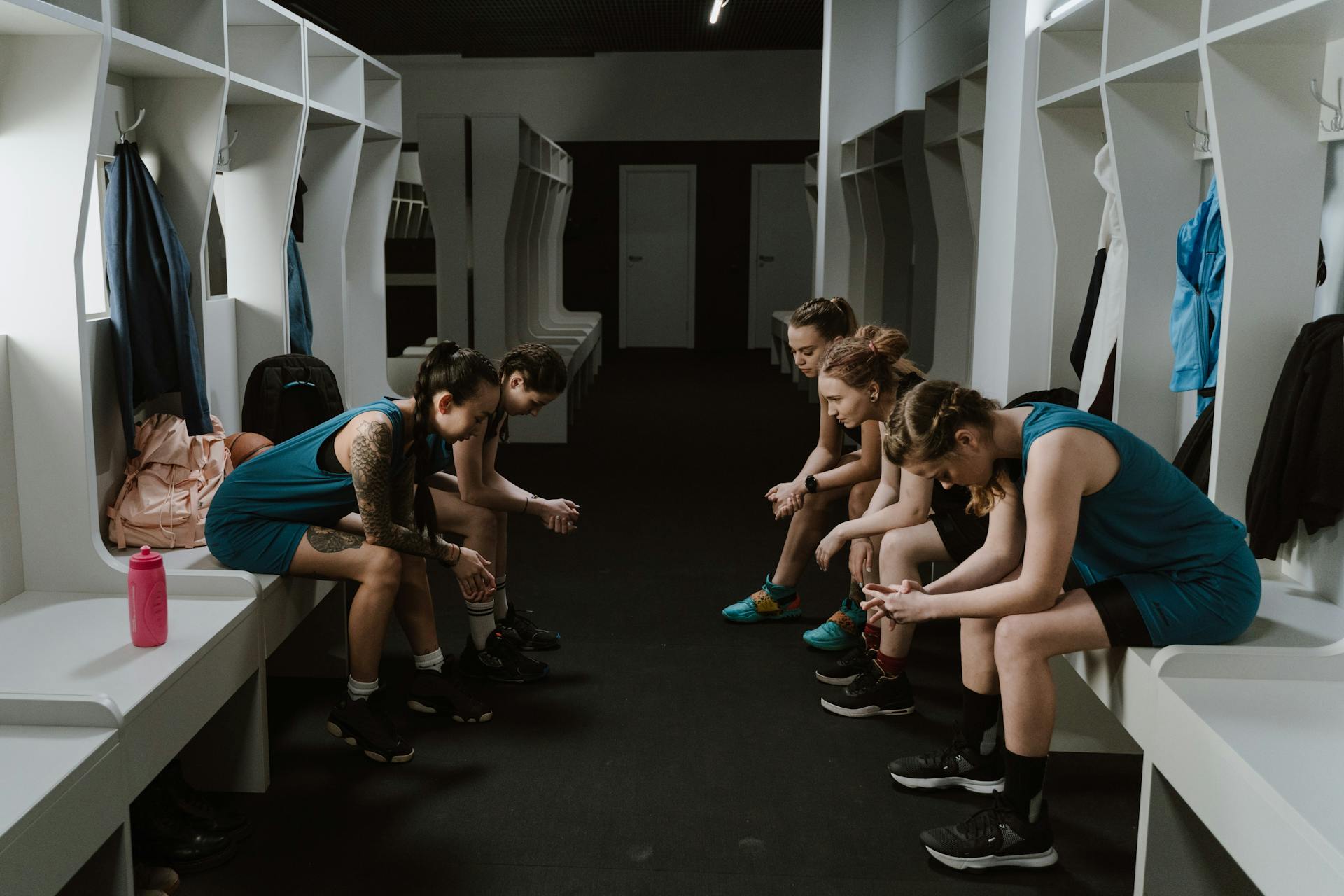 A group of women athletes resting in a locker room wearing sportswear.