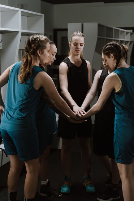 Team members joining hands together in unified circle huddle`